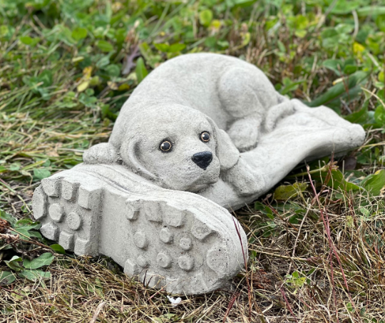 Concrete dog laying on boot statue