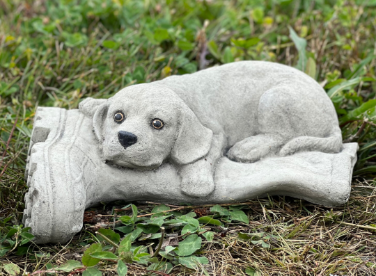 Concrete dog laying on boot statue