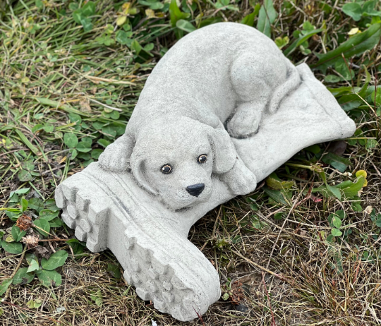 Concrete dog laying on boot statue