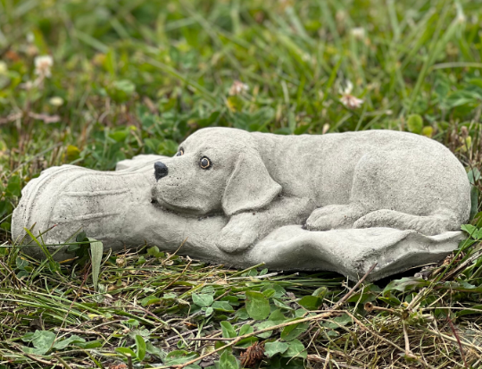 Concrete dog laying on boot statue