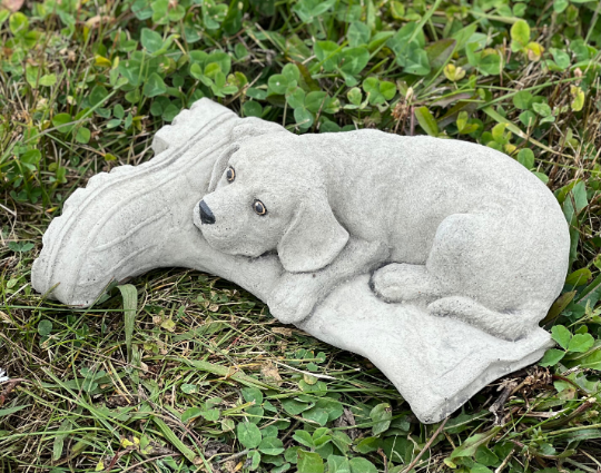 Concrete dog laying on boot statue