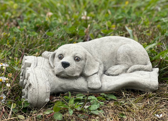 Concrete dog laying on boot statue