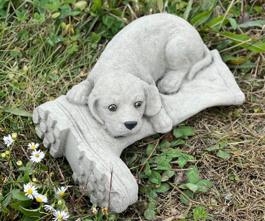 Concrete dog laying on boot statue